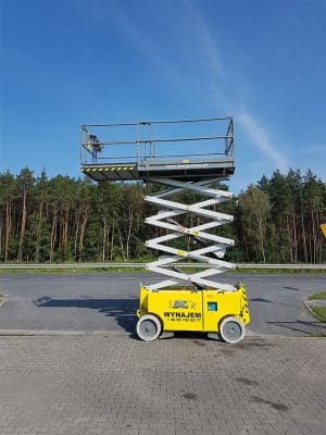 Scissor lift by the road next to the forest.
